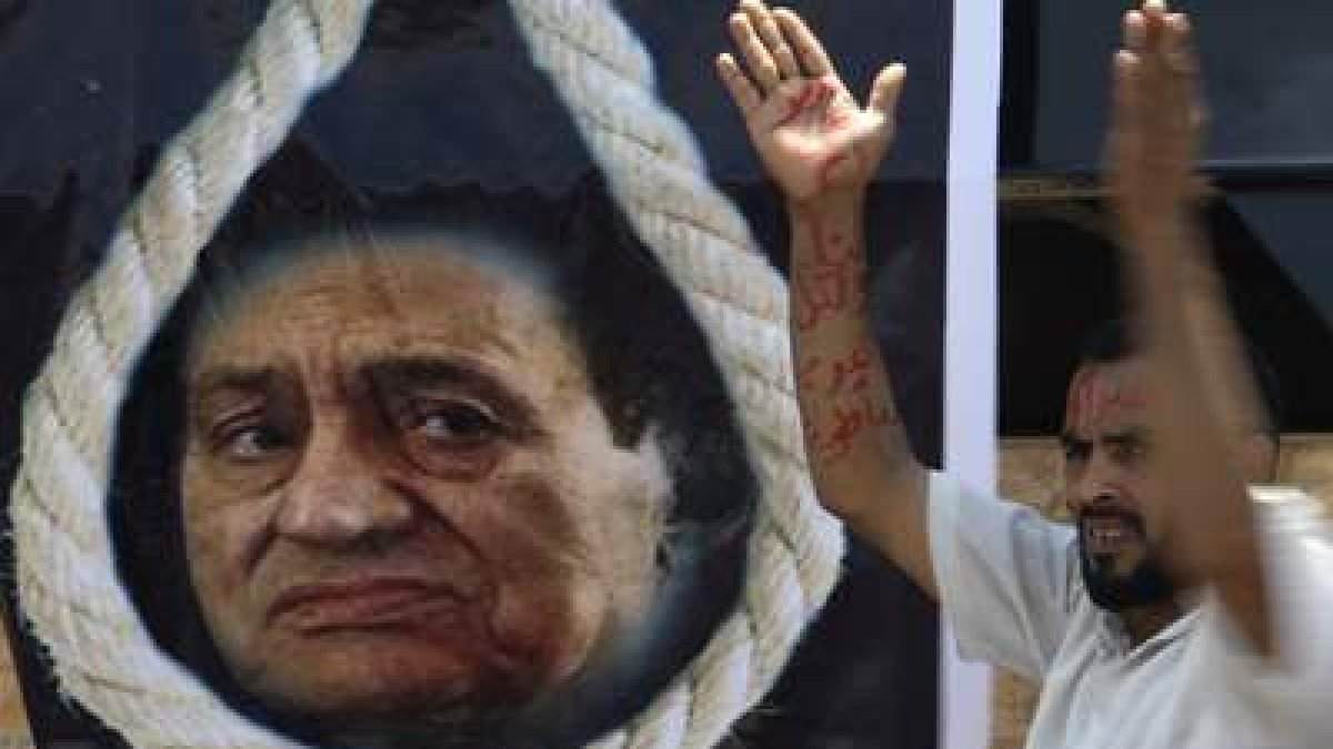 Un egipcio con las palabras «Egipto va primero» en su brazo, cerca de un cartel de Mubarak.