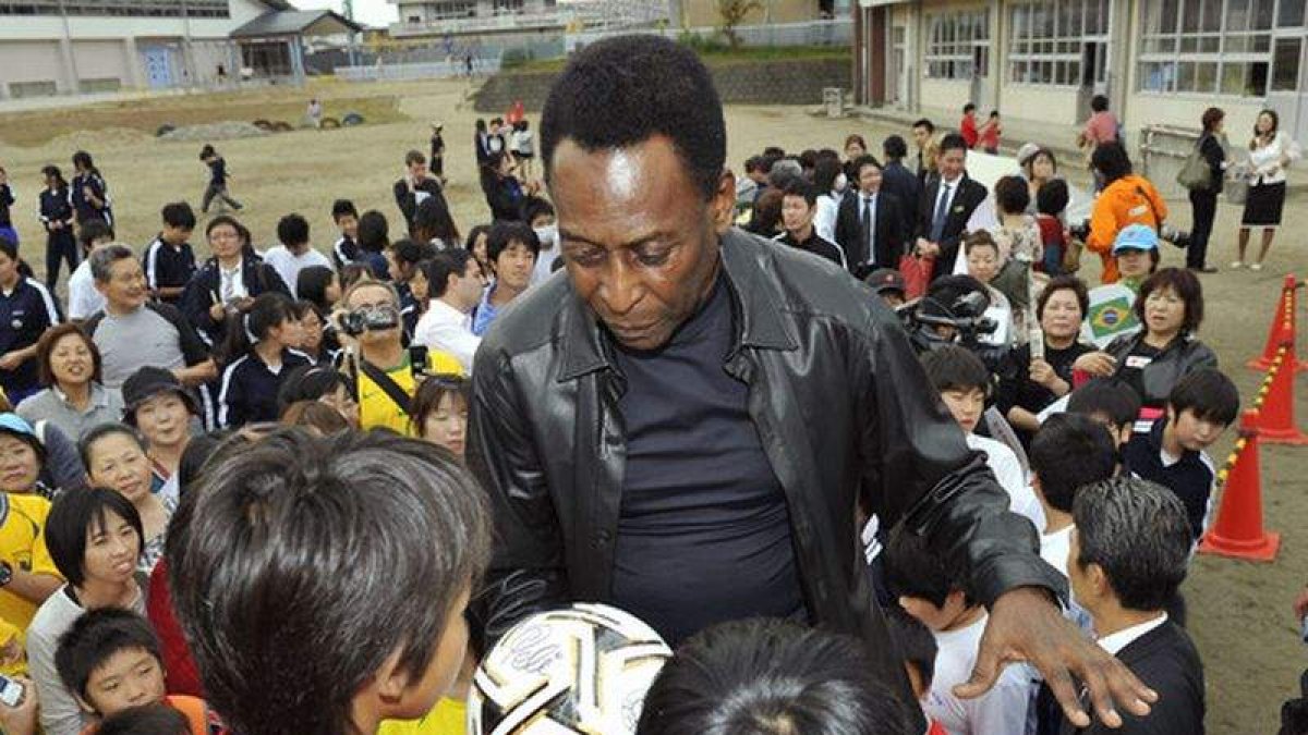 Pelé entrega un balón firmado a unos niños de una escuela de Fujigaoka, en Japón.