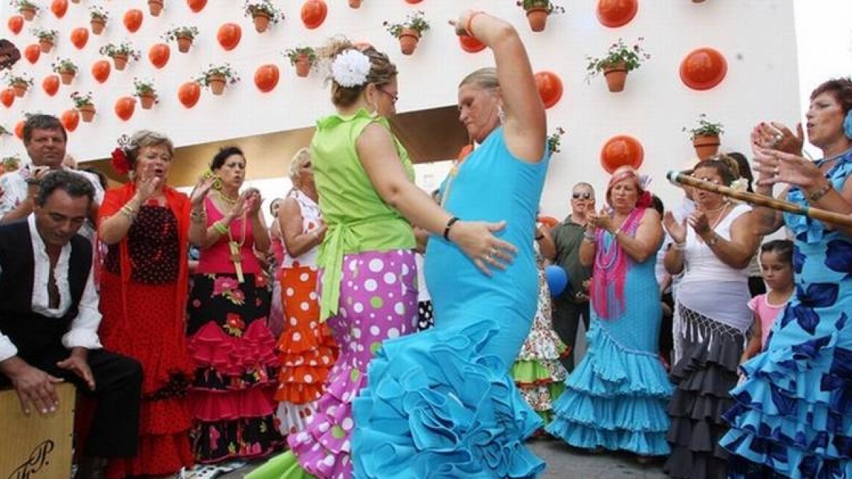 Unas mujeres bailan en un corrillo en el recinto ferial de Málaga, en las fiestas de agosto.