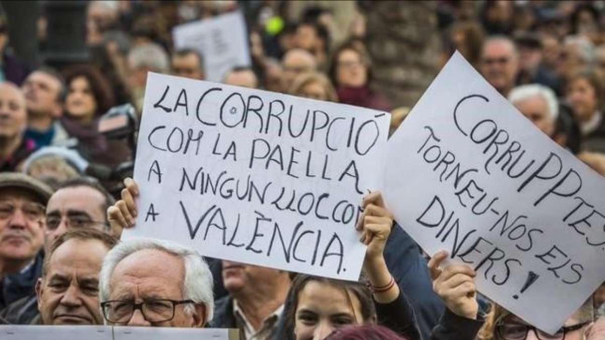 Asistentes a la manifestación contra la corrupción celebrada este domingo en Valencia portan carteles contra el PP y los casos que han afectado a esta comunidad.