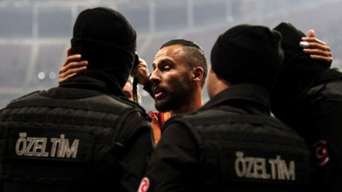Yasin Oztekin se abraza a dos policías en el estadio del Galatasaray.