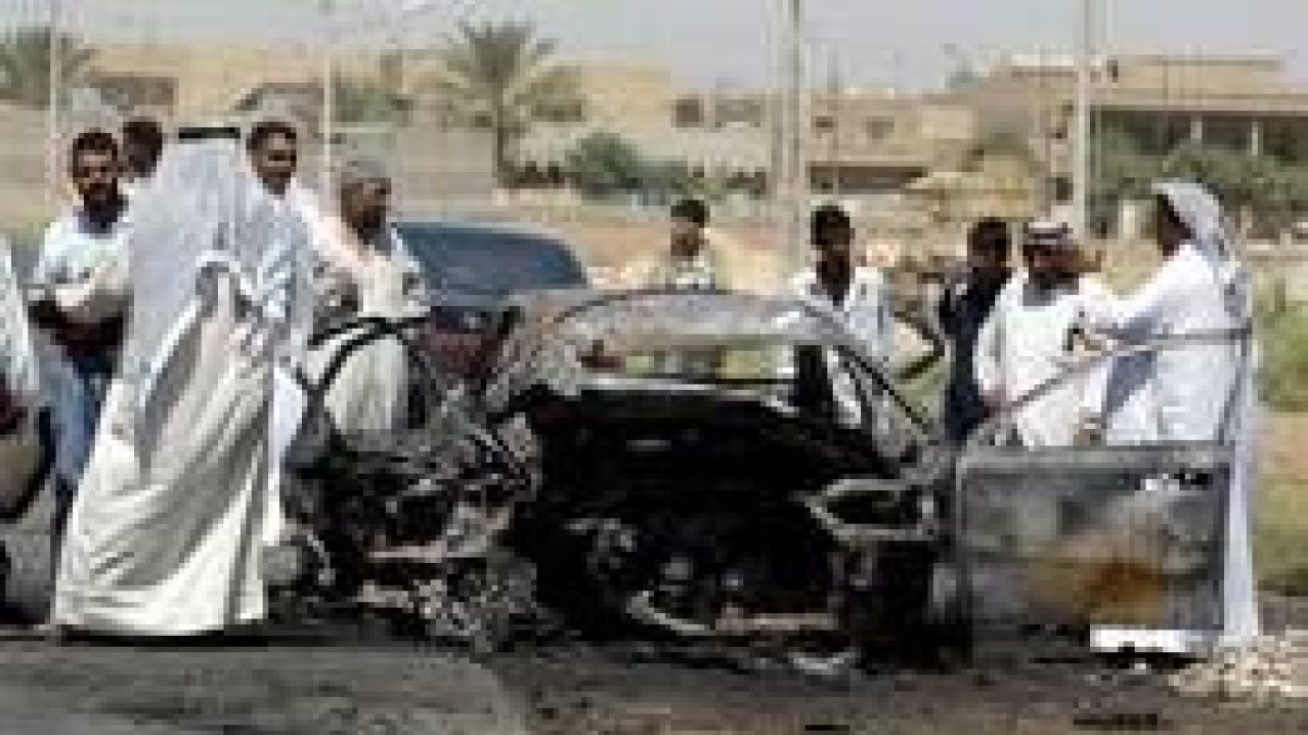 Unos iraquíes miran los restos del automóvil del diputado al Parlamento de Irak Ali Al Fayad