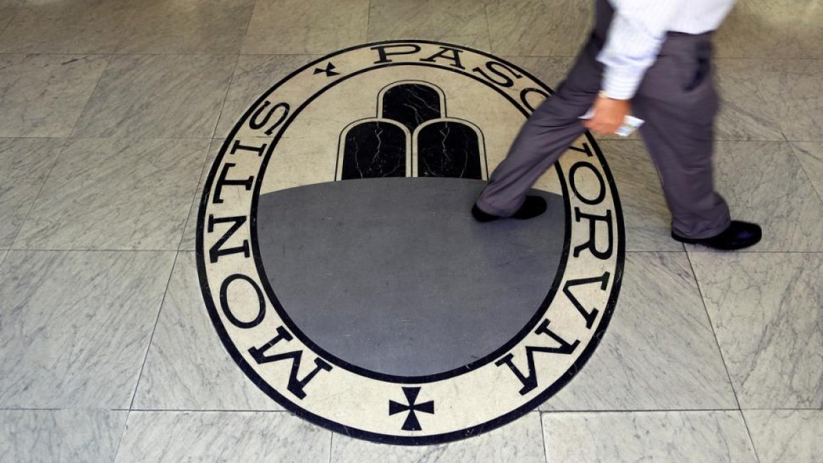 Un hombre camina sobre el logo del banco Monte Dei Paschi Di Siena en Roma.