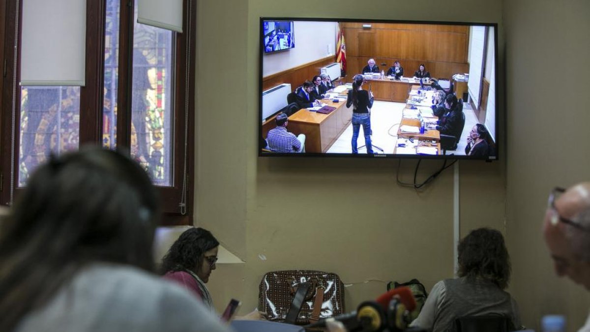 Periodistas siguen la declaración de una testigo por un monitor, en la Audiencia de Barcelona.