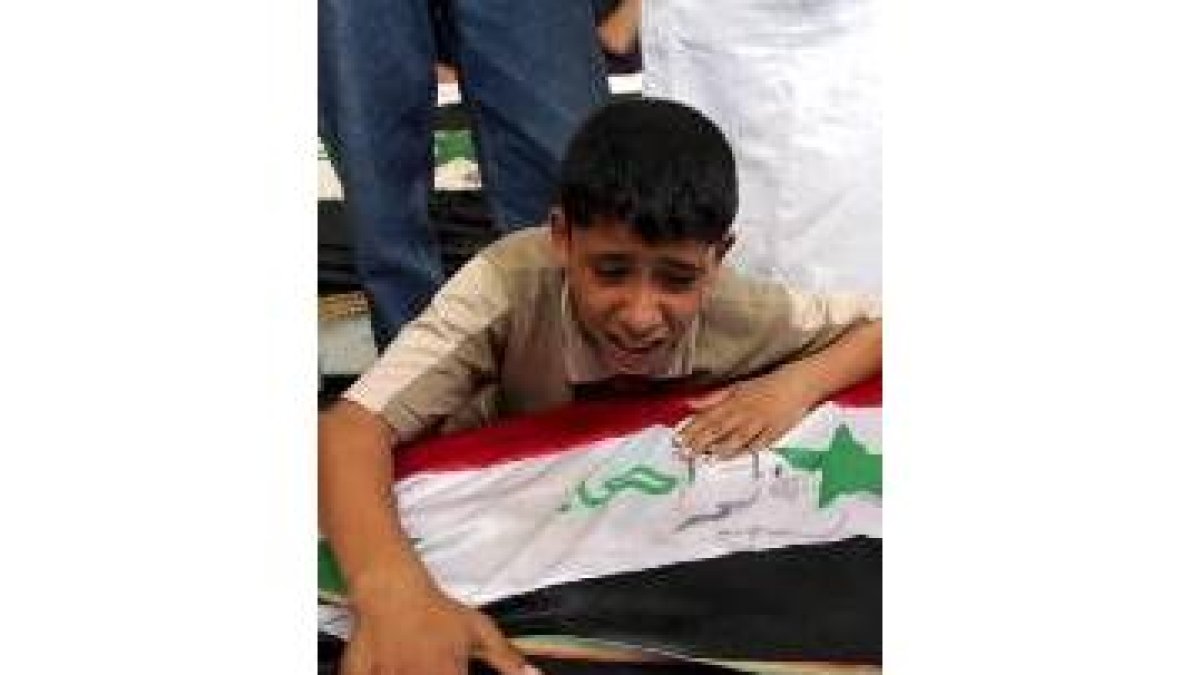 Una niño lllora desconsolado sobre el ataud de su padre en Bagdad