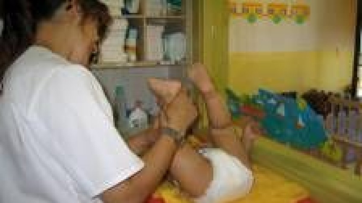 Una de las monitoras muestra cómo dar un masaje a un bebé en la guardería de San Andrés del Rabanedo