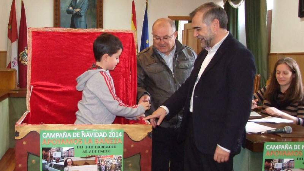 La ‘mano inocente’ entrega al alcalde la papeleta premiada en el sorteo.