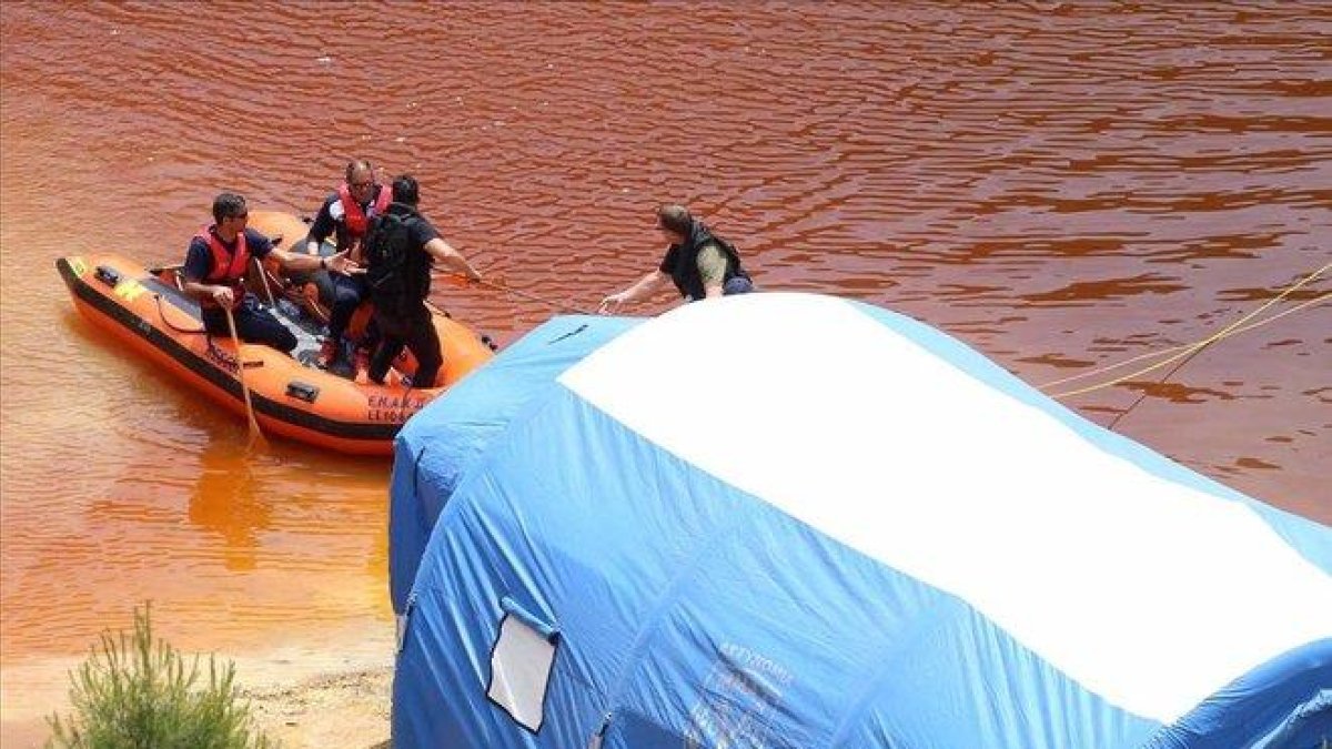 Miembros de los servicios de rescate navegan por el Lago Rojo mientras buscan nuevas pistas de los crímenes.