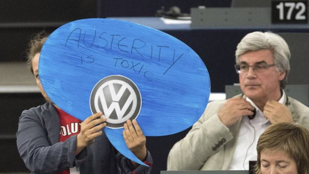 Una europarlamentaria alemana muestra un cartel en el que se lee "La austeridad es tóxica" y un logopito de la compañía Volkswagen durante la intervención de Angel Merkel en el Parlamento Europeo, ayer