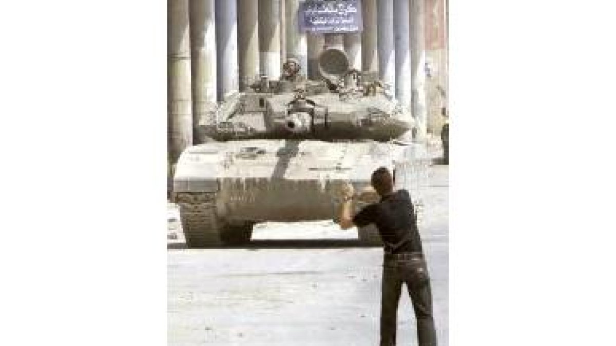 Un palestino lanza piedras contra un tanque israelí
