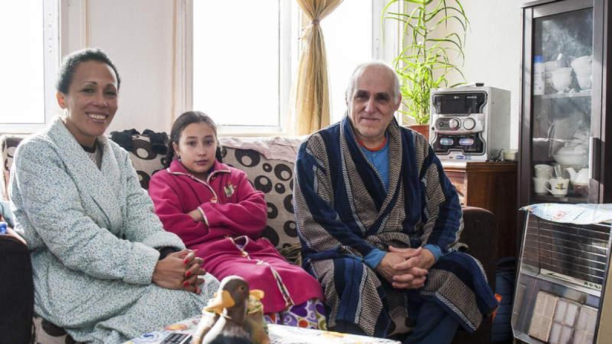 Carmen Elena y Florencio posan en el salón de su casa con su hija, abrigados para protegerse del frío sin poder poner la calefacción.