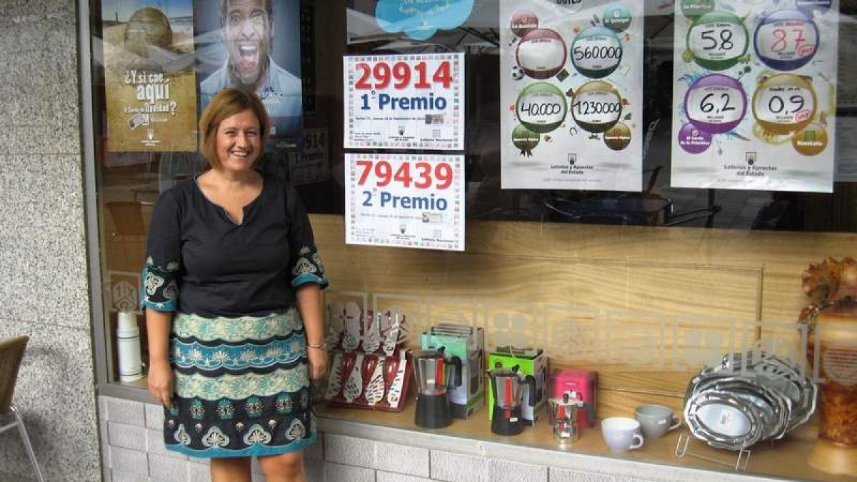 La propietaria del establecimiento, Cynthia Villar, junto a los carteles de los premios.