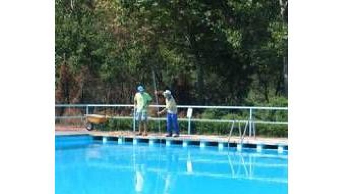 Dos técnicos de piscinas limpian el recinto antes de la hora de apertura al público