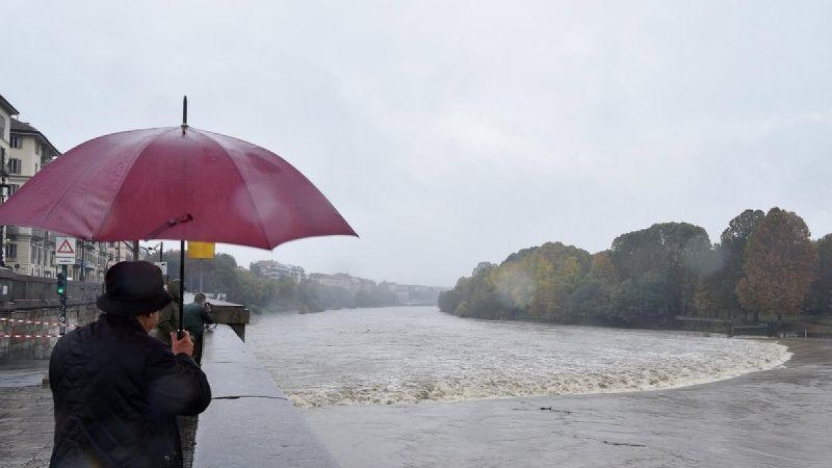 Varias personas observan la crecida del río Po durante unas fuertes lluvias en Turín. Cerca de once regiones italianas se encuentran en estado de emergencia debido a las lluvias y tormentas de los últimos días.