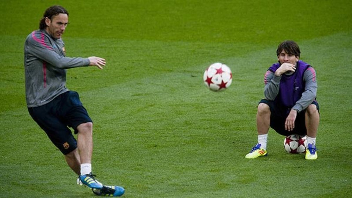 Messi observa a Milito golpeando el balón, durante un entrenamiento en el 2011.