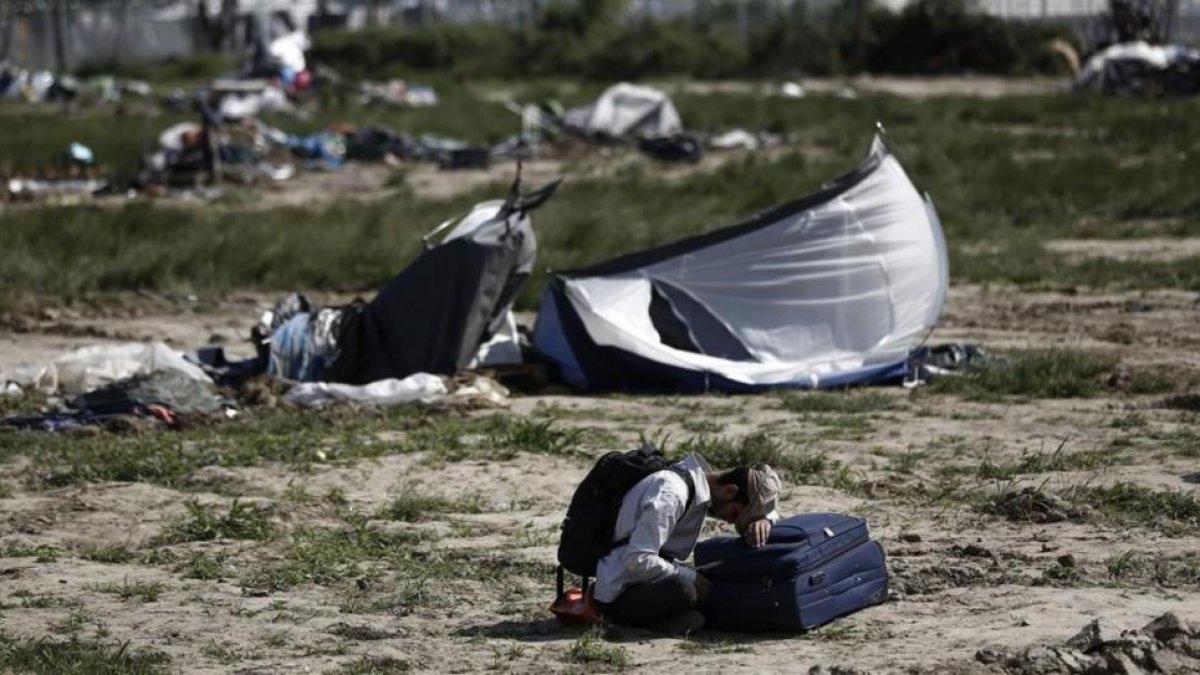 Un kurdo espera sentado junto a su maleta el momento de abandonar Idomeni.