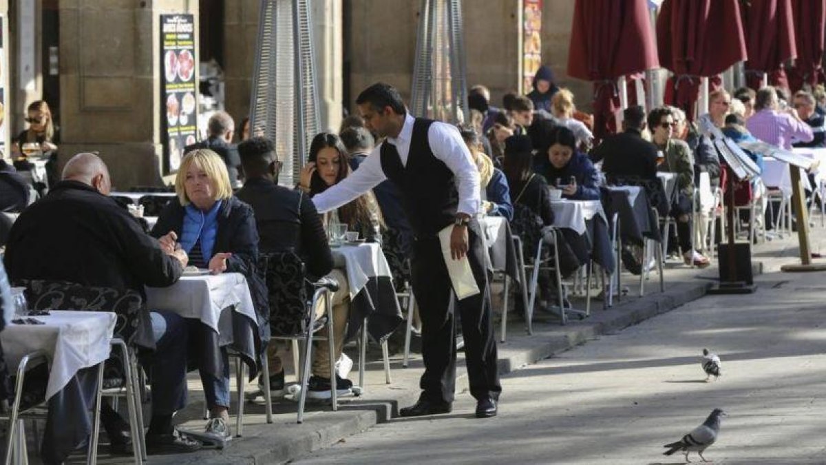 Un camarero sirve unas mesas en un restaurante.