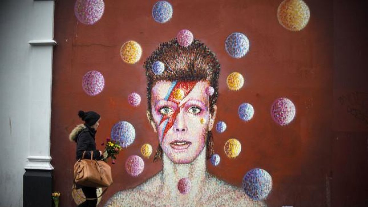 Flores ante un mural de David Bowie en la pared del comercio Morley, en Brixton (Londres), lugar de nacimiento del cantante.