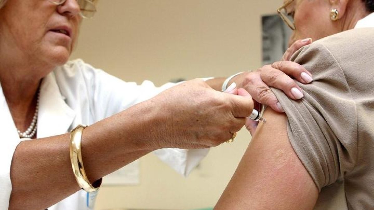 Una enfermera pone una vacuna contra la gripe  a una paciente. ICAL.