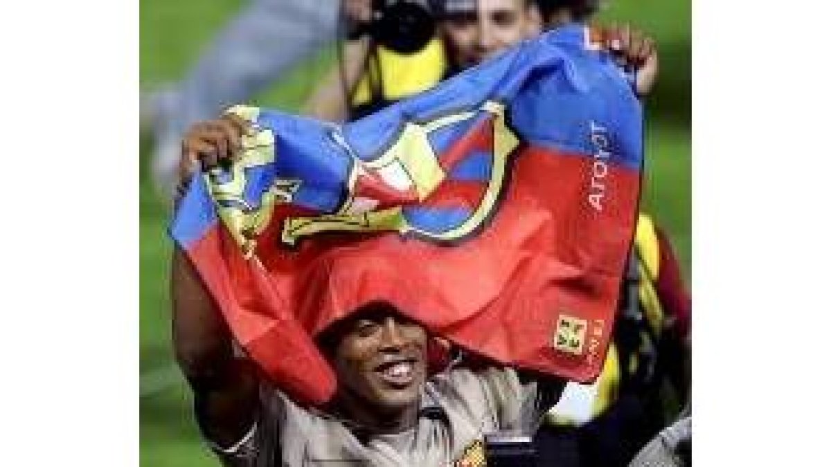 Ronaldinho ondea una bandera con los colores azulgrana tras conseguir el título de liga