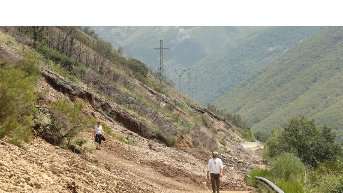 Dos vecinos de Valseco, ayer, saliendo del pueblo andando tras una travesía de tres kilómetros y medio. En la imagen se pueden ver los efectos del derrumbre a lo largo de varios metros.L. DE LA MATA