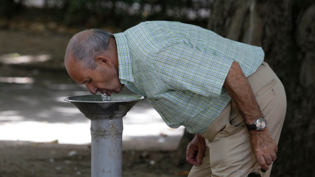 Un hombre bebe agua en una fuente pública en León. FERNANDO OTERO