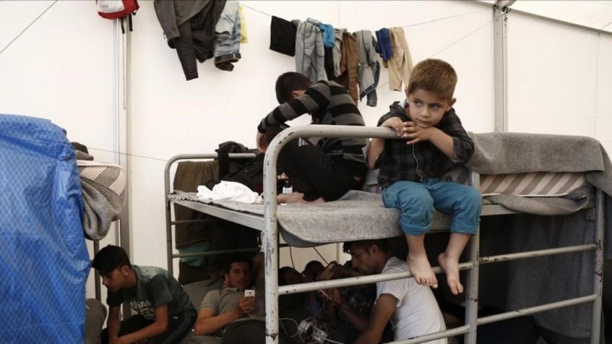 Una familia afgana encuentra refugio dentro de una tienda en un campamento de tránsito al oeste de Atenas.