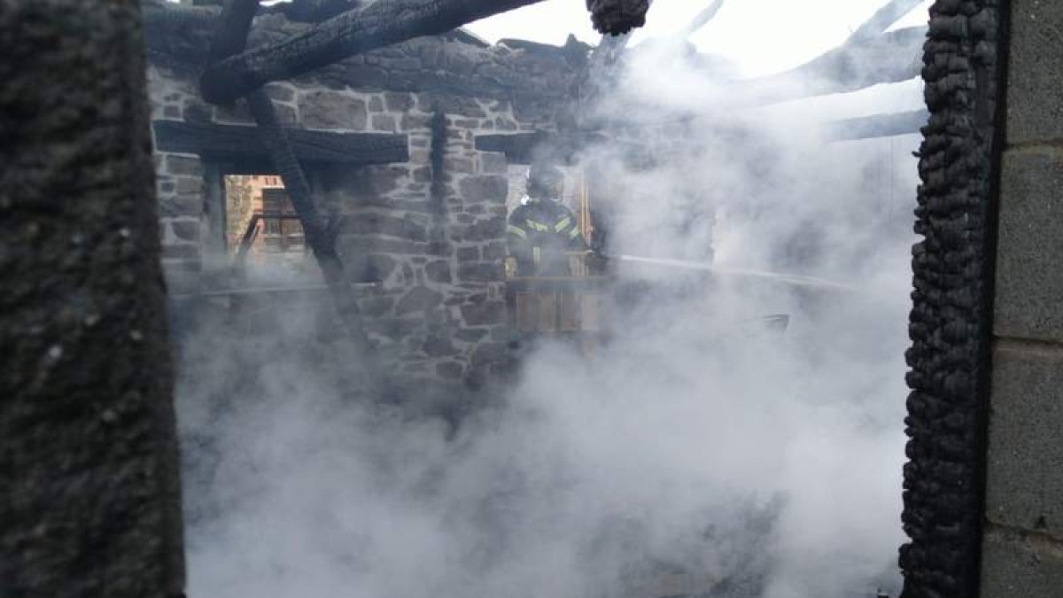 Un bombero trabaja en la extinción del fuego en la vivienda de Tombrio. BOMBEROS PONFERRADA
