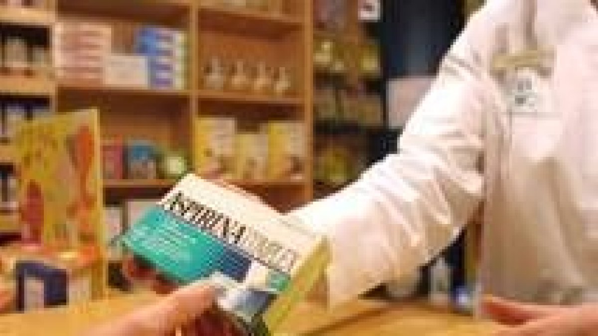 Una farmacéutica dispensa una caja de aspirinas en un establecimiento en la capital leonesa
