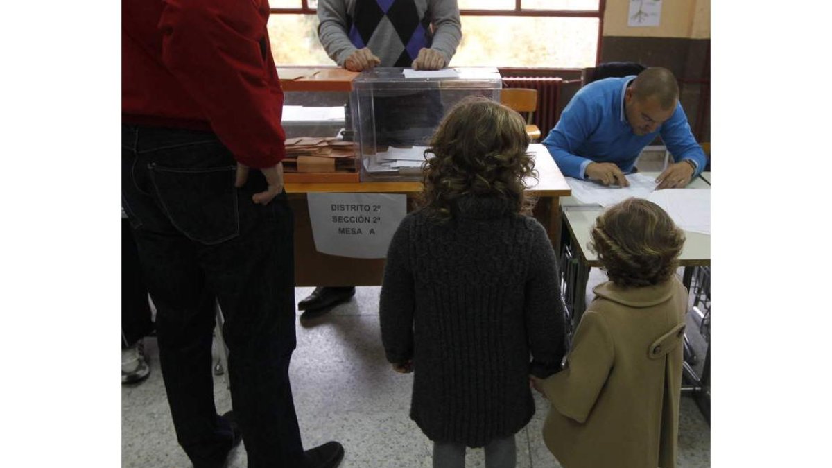 Dos niños siguen la votación en un colegio.