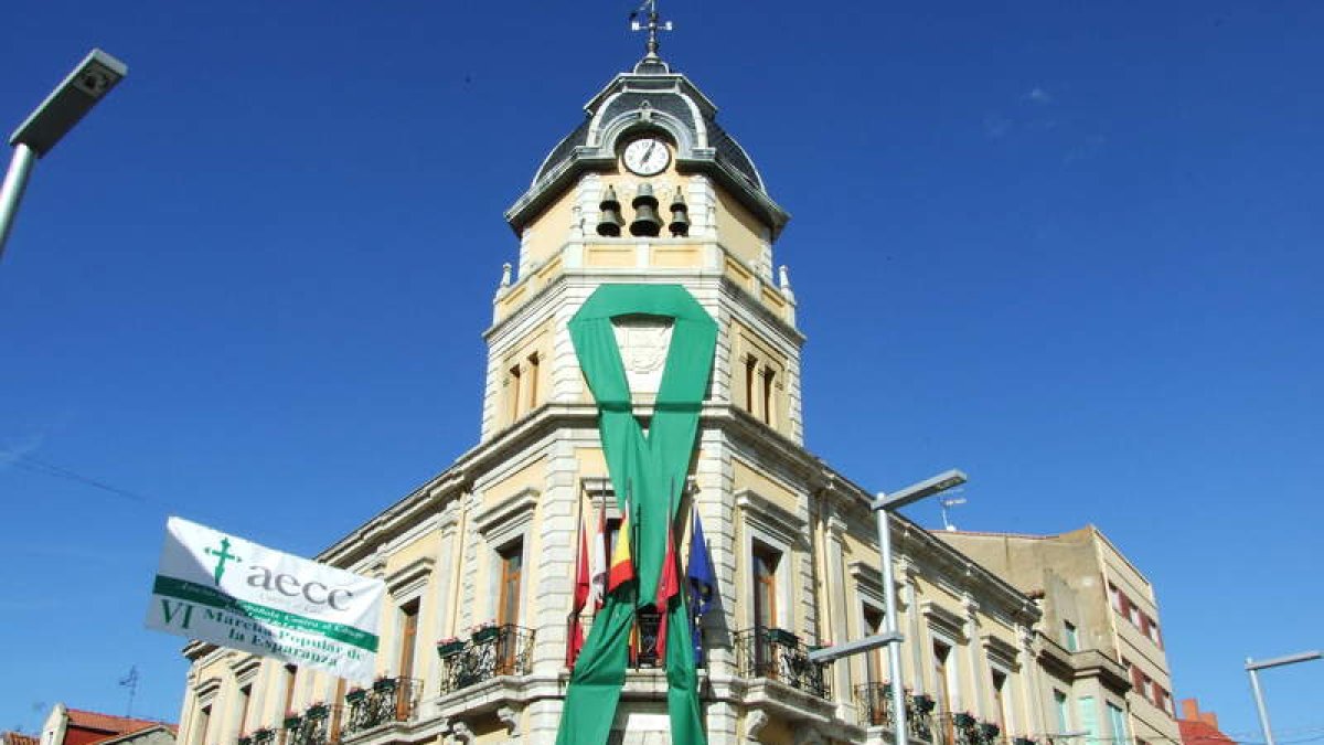 La junta local de la AECC ha colocado un inmenso lazo verde en en el Ayuntamiento bañezano.