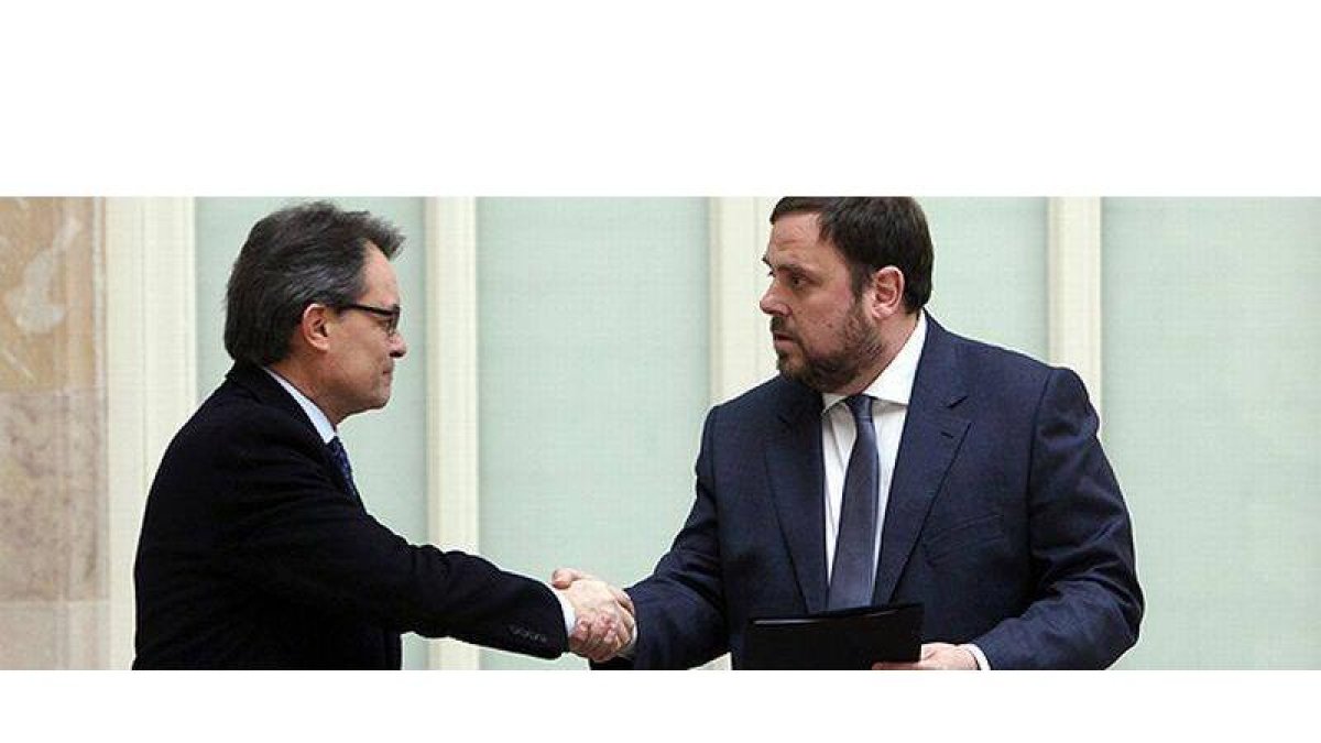 Artus Mas y Oriol Junqueras se saludan tras la firma del acuerdo en el Parlament.