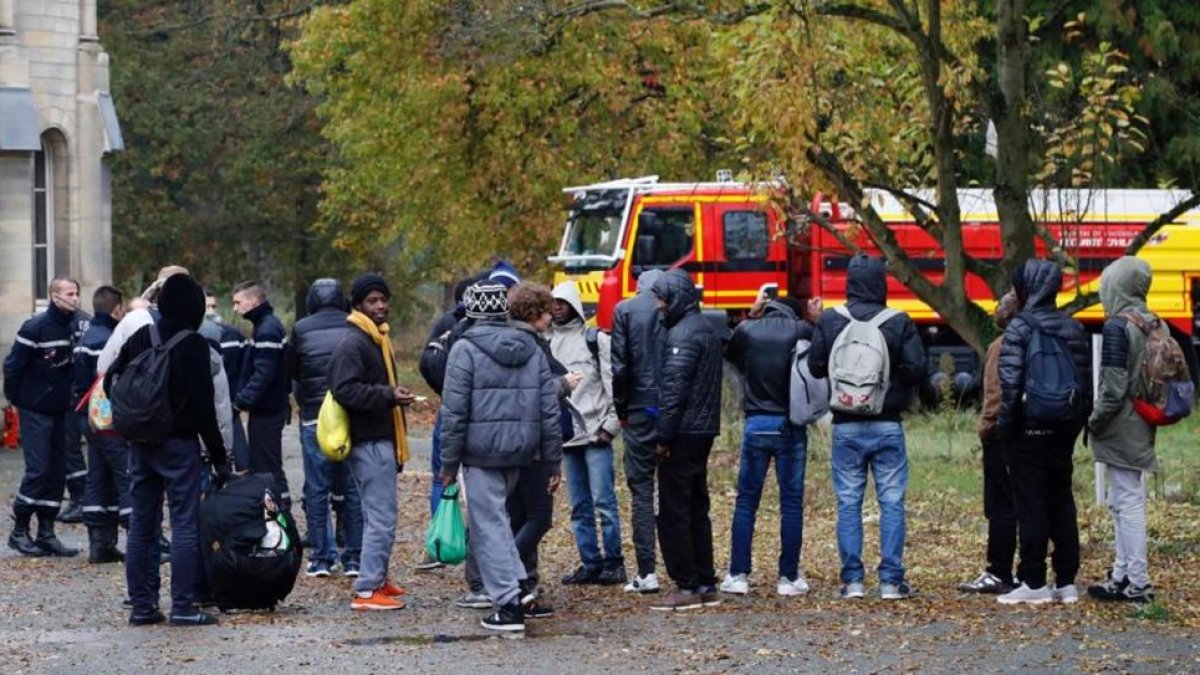 Migrantes acompañados por miembros de la seguridad civil francesa, a su llegada a un nuevo alojamiento en Sarcelles, en el norte de París, este viernes.
