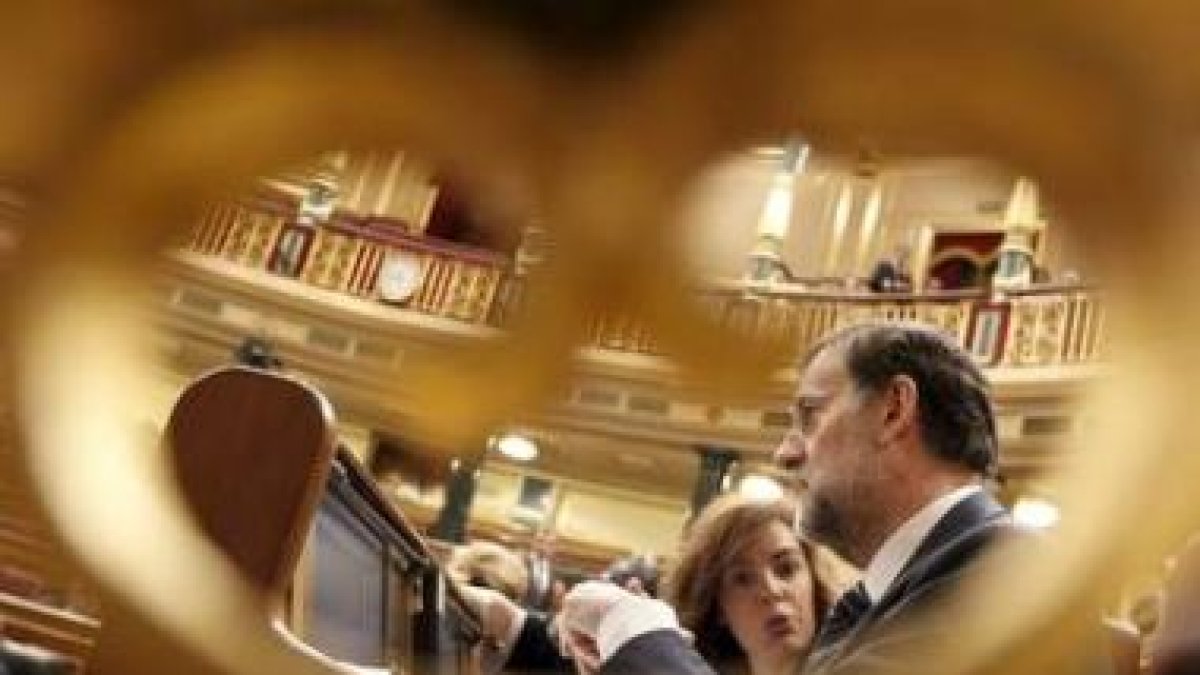 Sáenz de Santamaría y Rajoy conversan sentados en sus escaños en el Congreso de los Diputados.