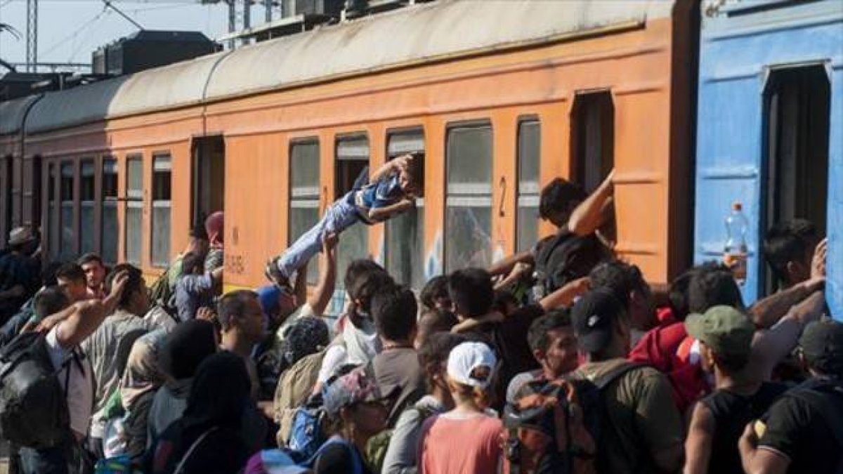 Decenas de inmigrantes y refugiados intentan subir a un tren en una estación de Macedonia con destino a Serbia, el martes.