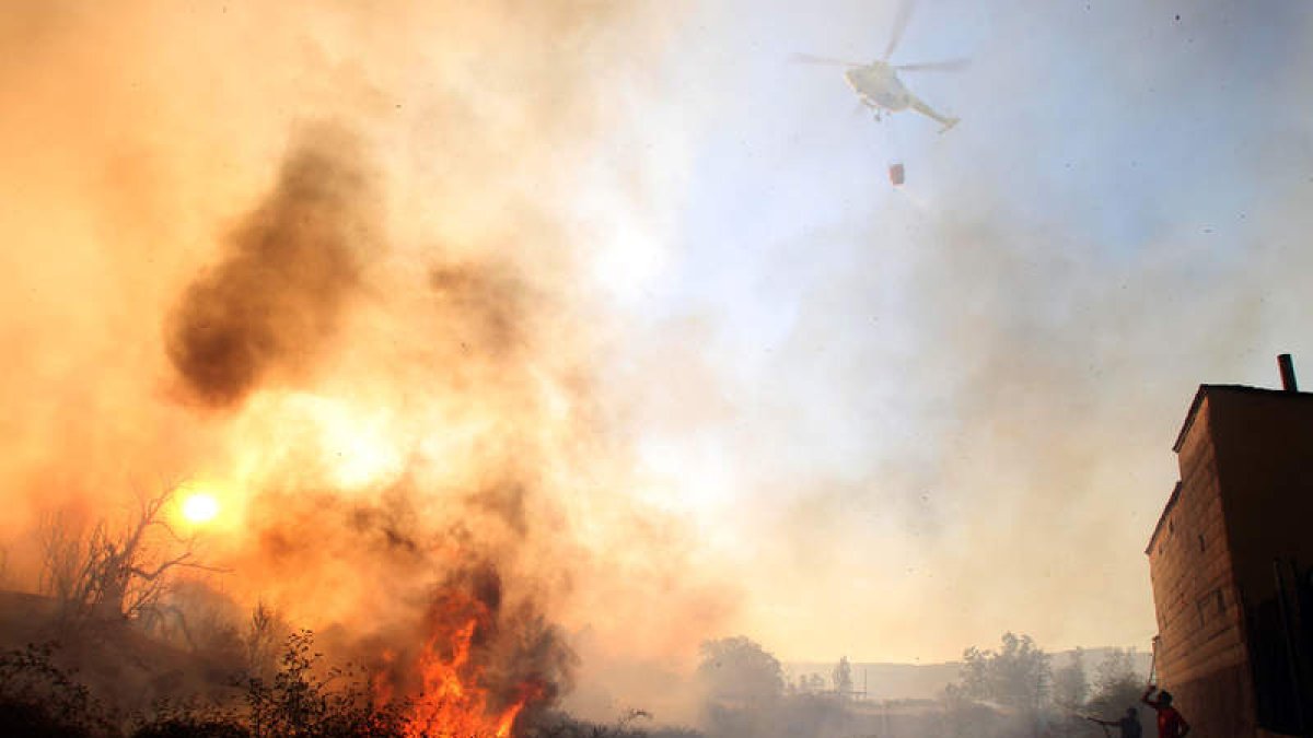 Un helicóptero vierte agua en un momento en el que las llamas amenazan las casas de Molina.