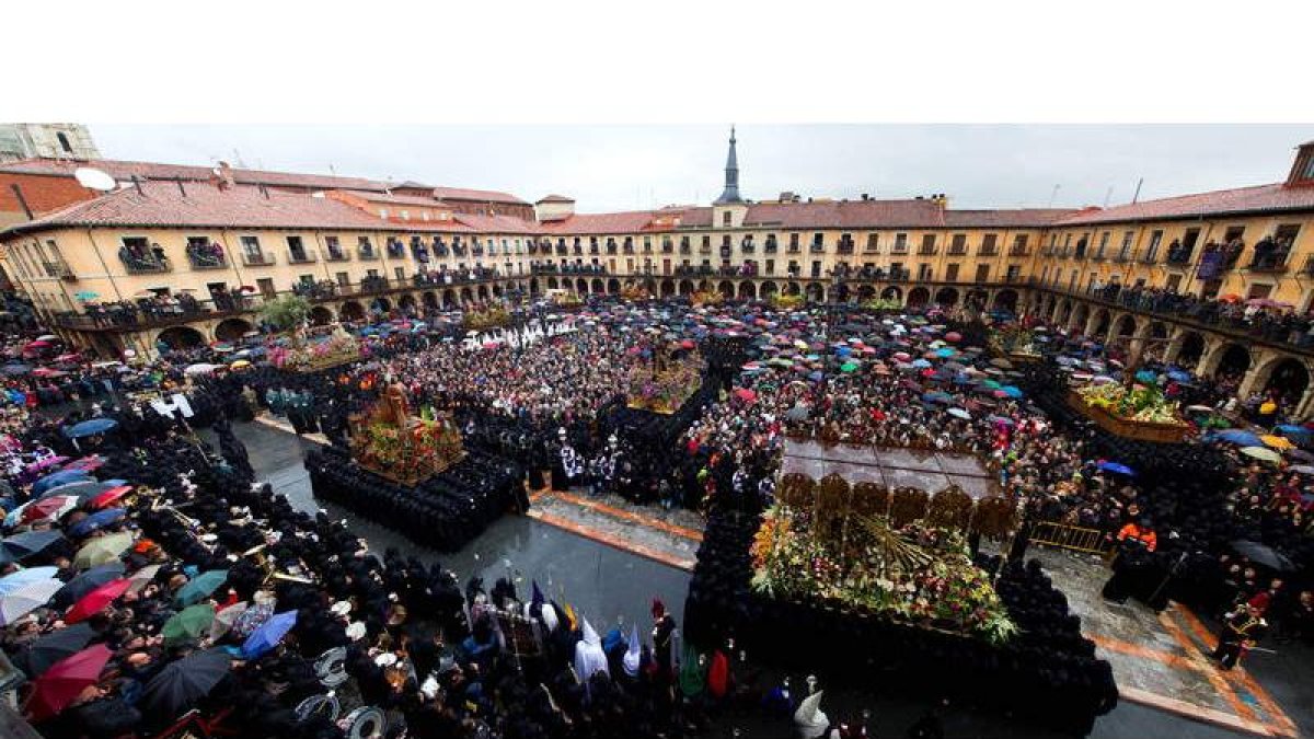 Los braceros de San Juanín y la Virgen inician el ritual del Encuentro en la plaza Mayor, con miles de personas protegiéndose con paraguas del fuerte aguacero que obligó a recoger la procesión de Los Pasos en ordinaria.