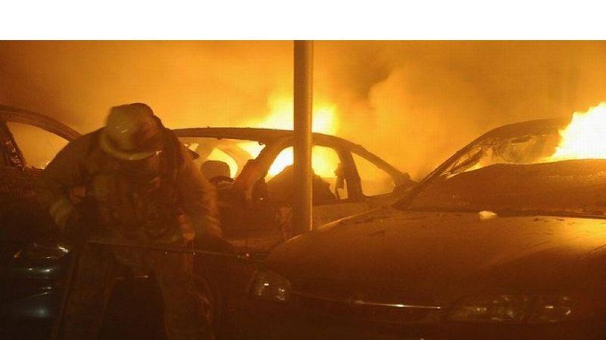 Bomberos intentan apagar coches incendiados en Los Ángeles, este lunes.