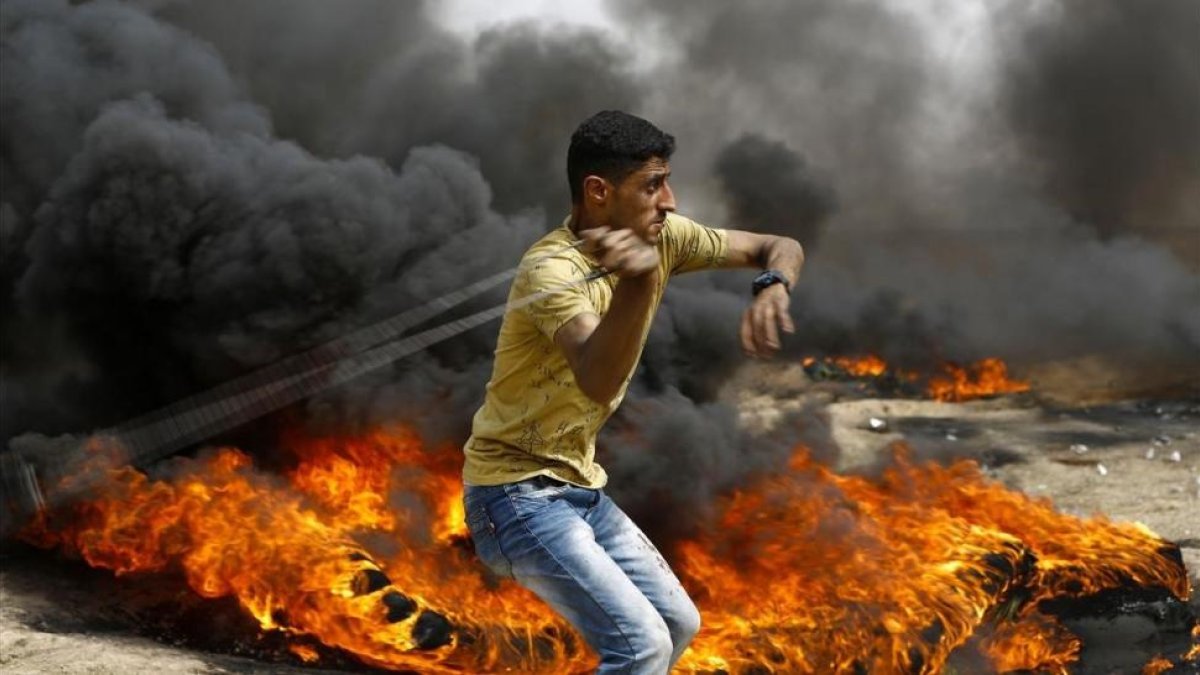 Un palestino se dispone a lanzar piedras entre los neumáticos incendiados contra las tropas israelís, en las protestas junto a la frontera de la Franja de Gaza, el 20 de abril.