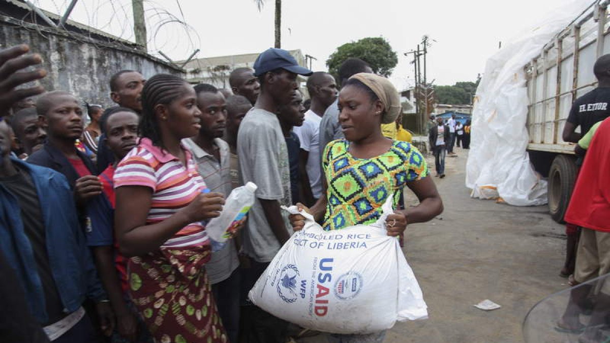 Varios liberianos reciben raciones de comida como parte del plan de cuarentena.