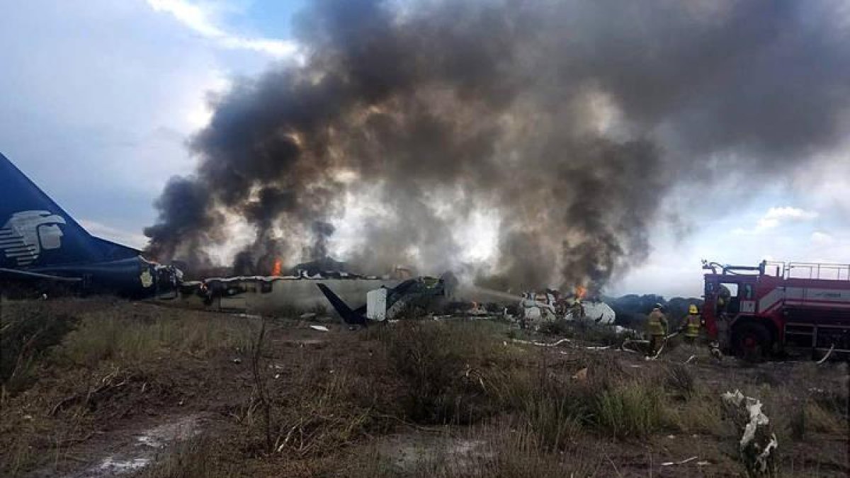 El avión destrozado y en llamas en el suelo