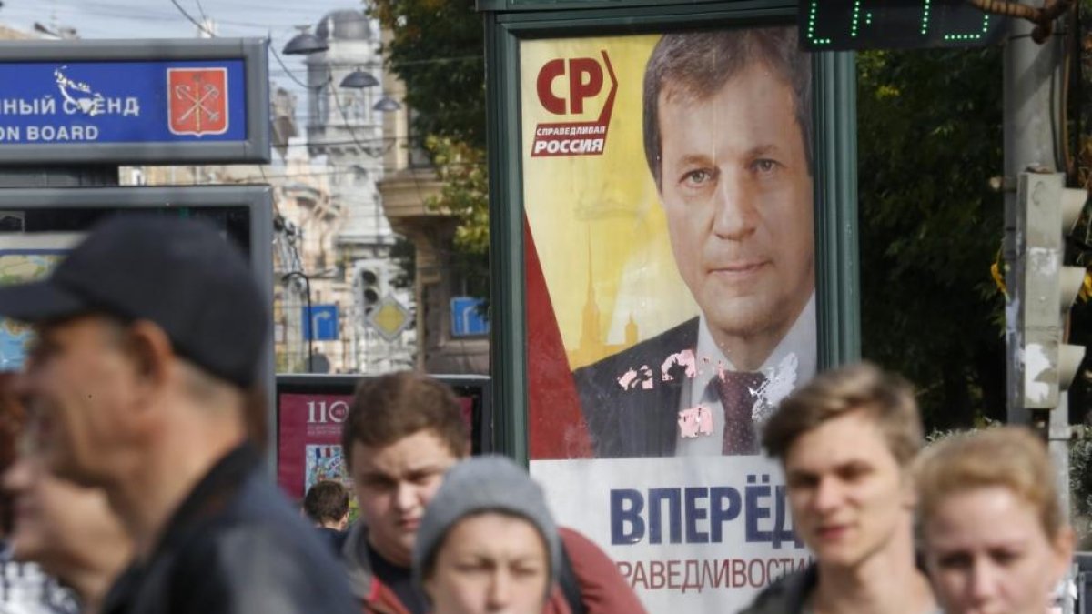 Peatones pasas por delante de un cartel electoral en San Petersburgo.
