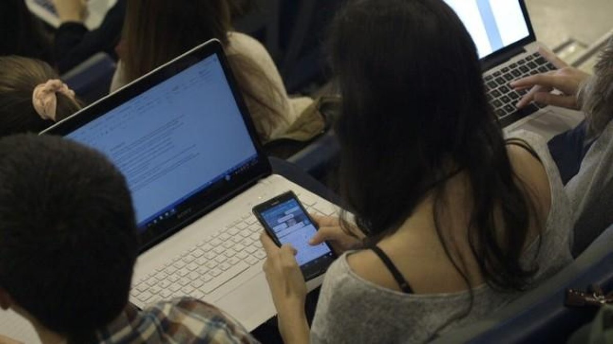 Una joven consulta el móvil mientras estudia en la universidad.