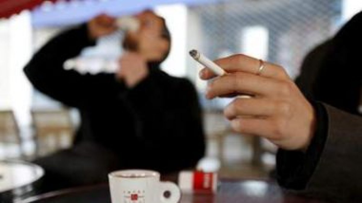 Unos clientes descansan mientras se toman un café y se fuman un cigarro.