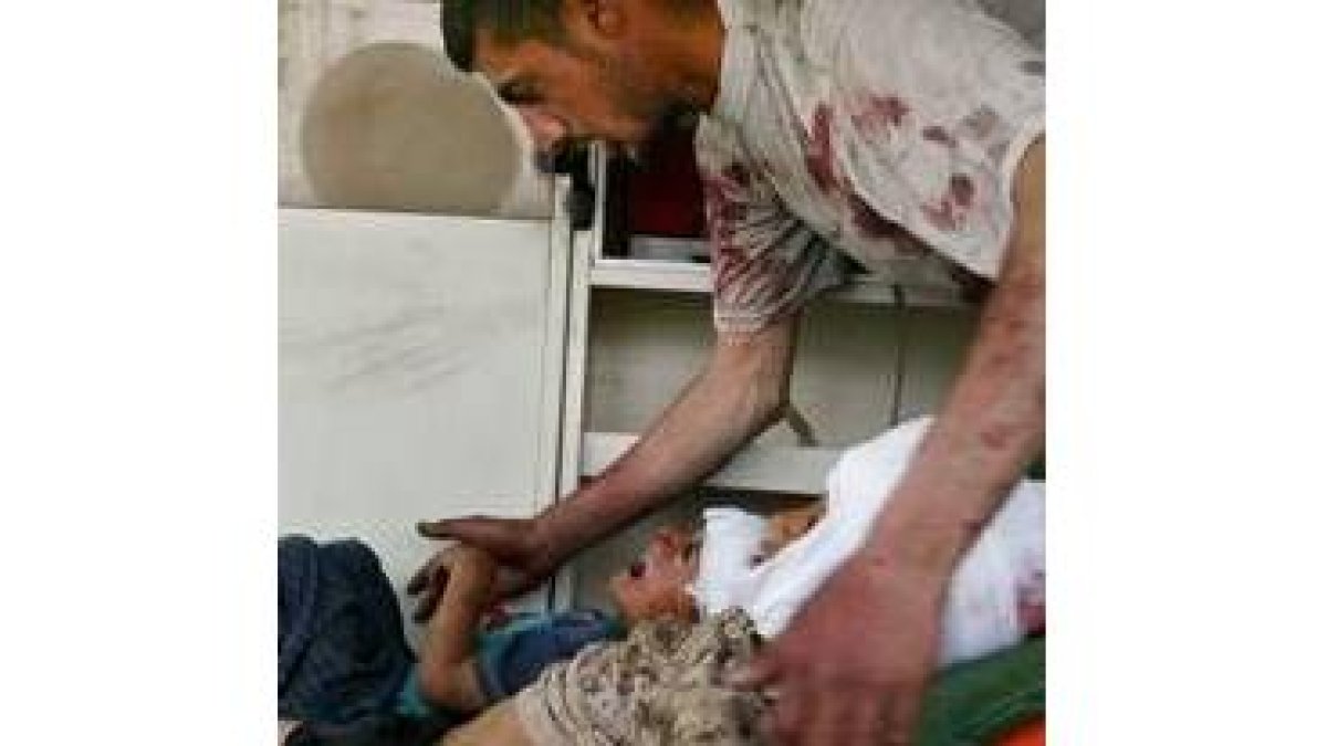 Un iraquí consuela a dos niños heridos en el atentado de Bagdad