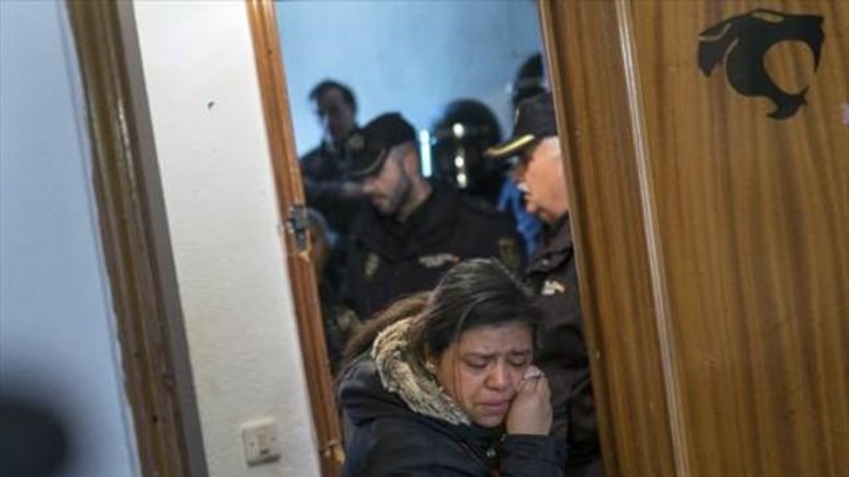 Una mujer abandona llorando la casa ocupada en la que vivía con su familia, tras ser desahuciada por la policía.