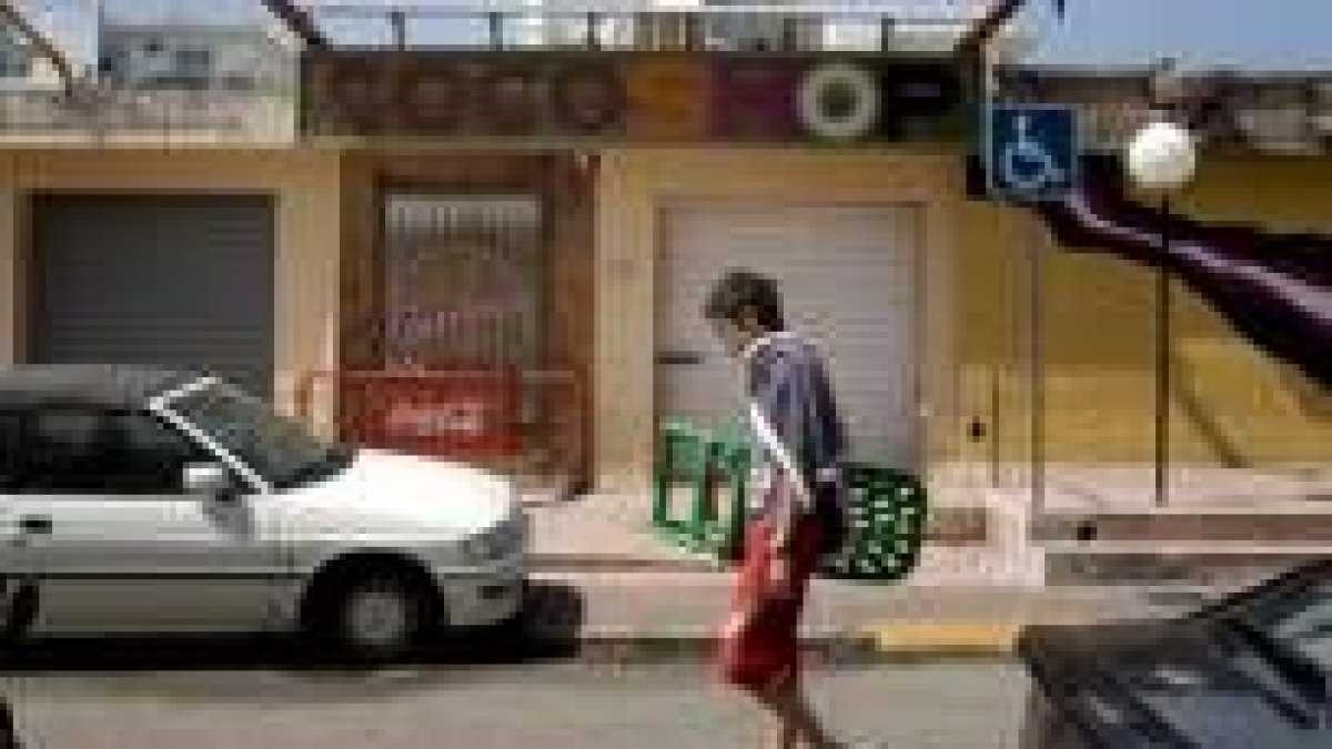 Un veraneante pasa ante la tienda «Cocoloco», de Gandía, donde una mujer de 20 años fue asesinada