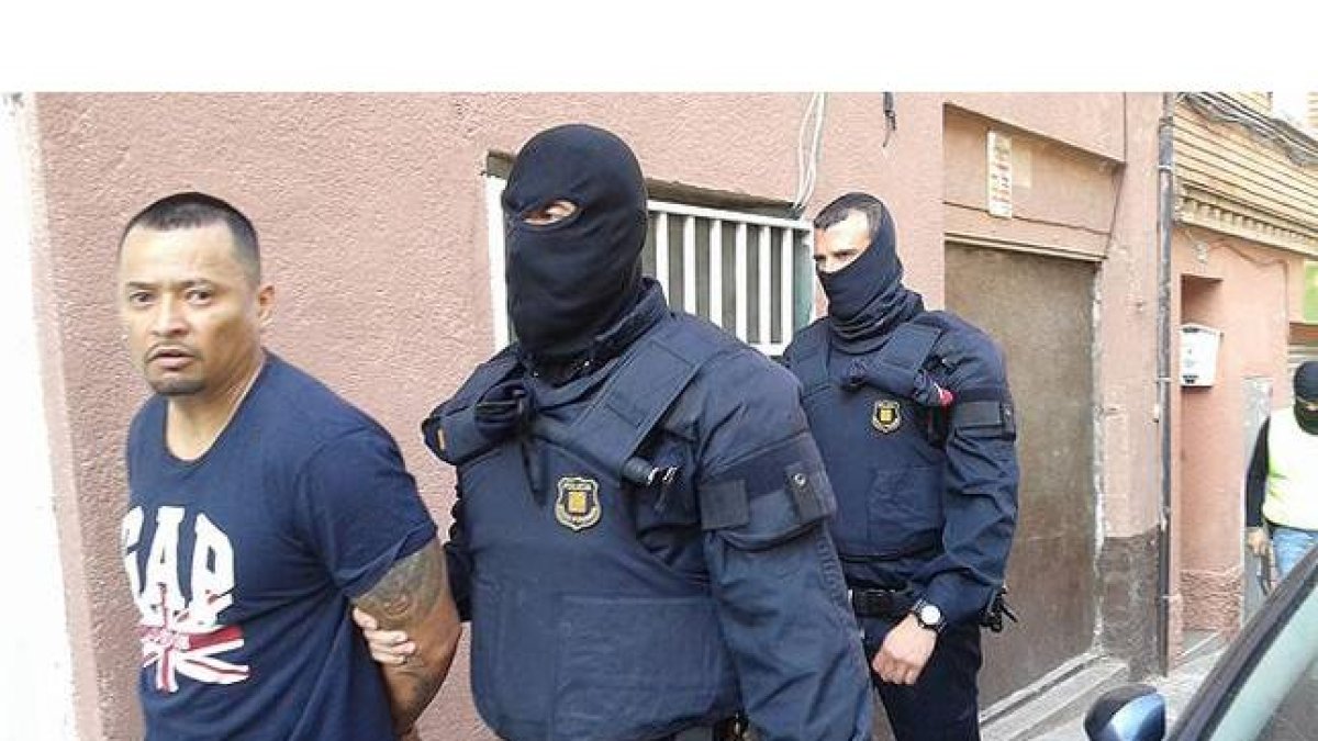Imagen cedida por la Cadena Ser, en la que dos mossos se llevan detenido, en Santa Coloma de Gramenet, a uno de los presuntos miembros de la banda de Latin Kings desarticulada este miércoles.