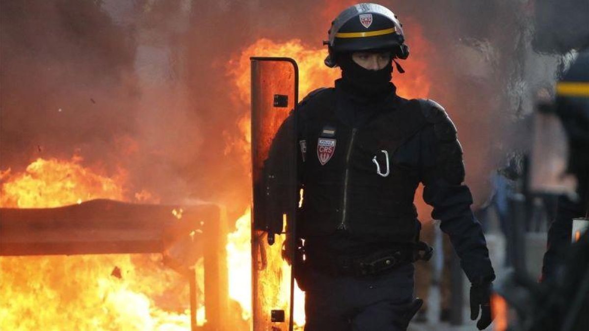 Un policía antidisturbios camina cerca del fuego de una barricada en Toulouse.