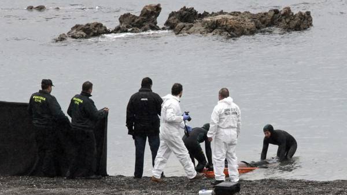 Agentes de la Guardia Civil retiran el cuerpo del subsahariano encontrado en la playa de Tarajal de Ceuta.